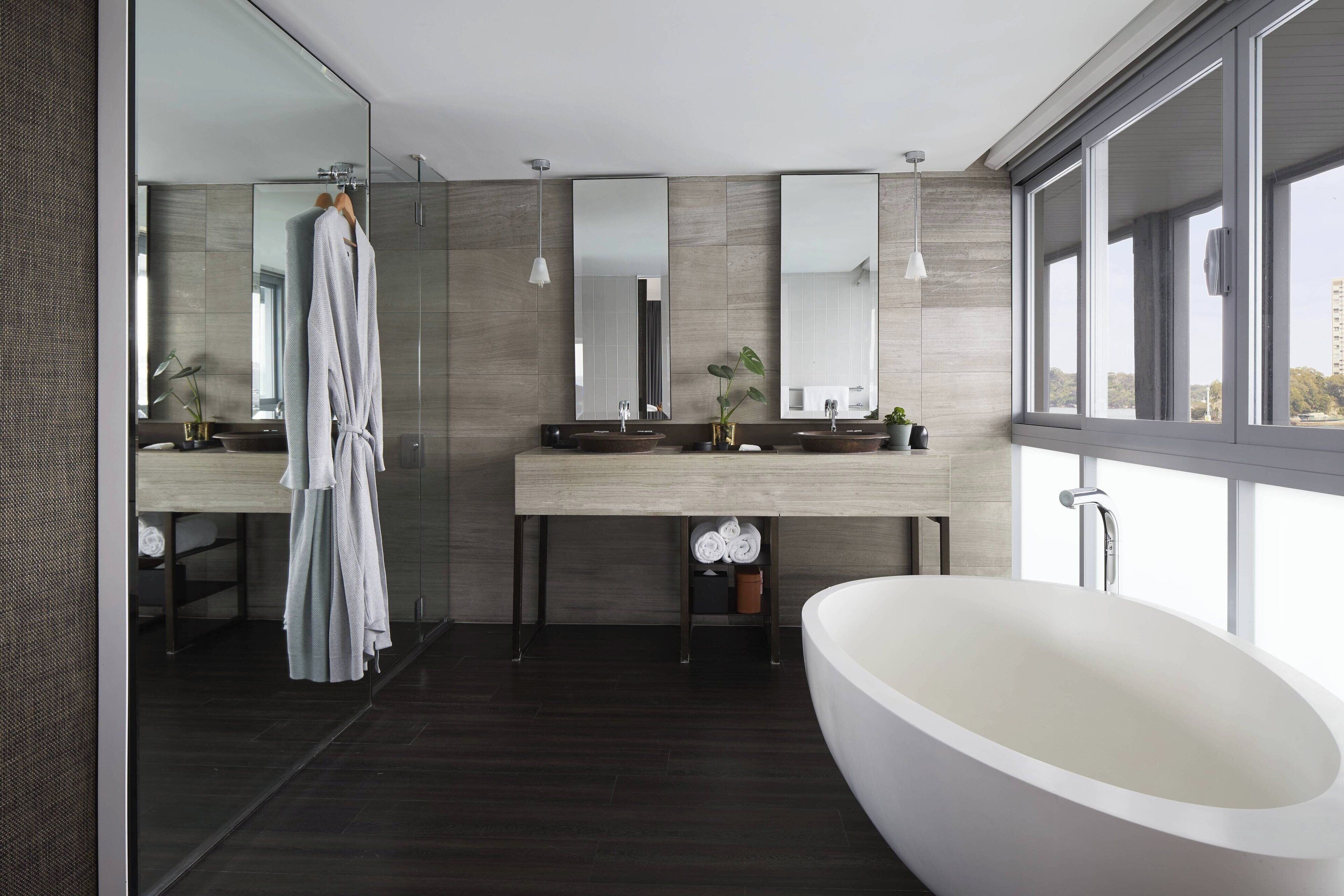A modern bathroom with a large bathtub, a glass shower enclosure, and a vanity with two sinks.