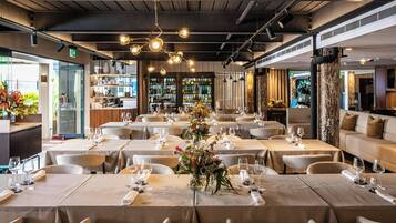 A restaurant with multiple tables set for dining, featuring a central floral arrangement.