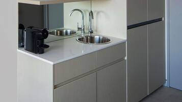A modern kitchen with a built-in sink, a coffee maker, and a microwave on a light-colored countertop.