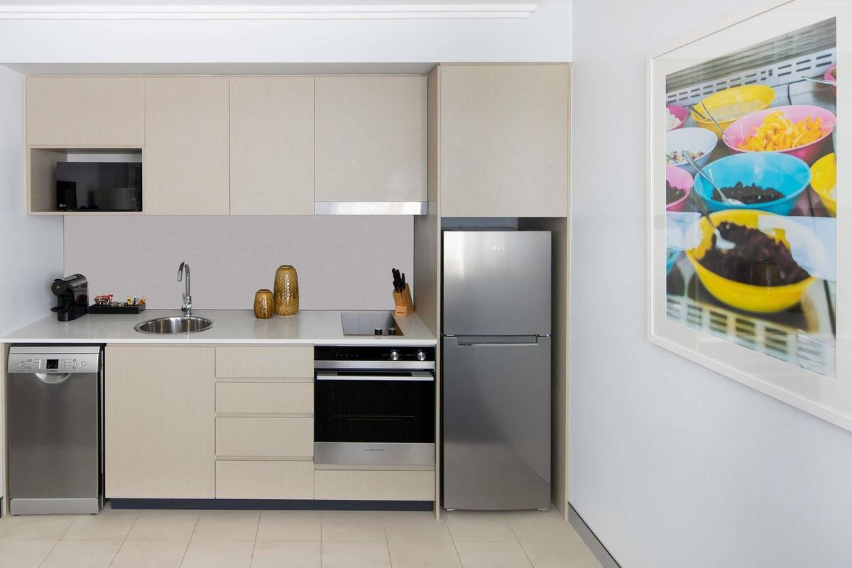 A modern kitchen with a dishwasher, oven, and refrigerator.