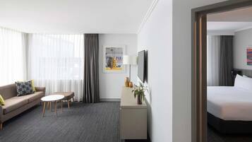 Ein Hotelzimmer mit Bett, einer Couch, einem kleinen Tisch, einem Fernseher und einem Schreibtisch mit Lampe und Dekoration.