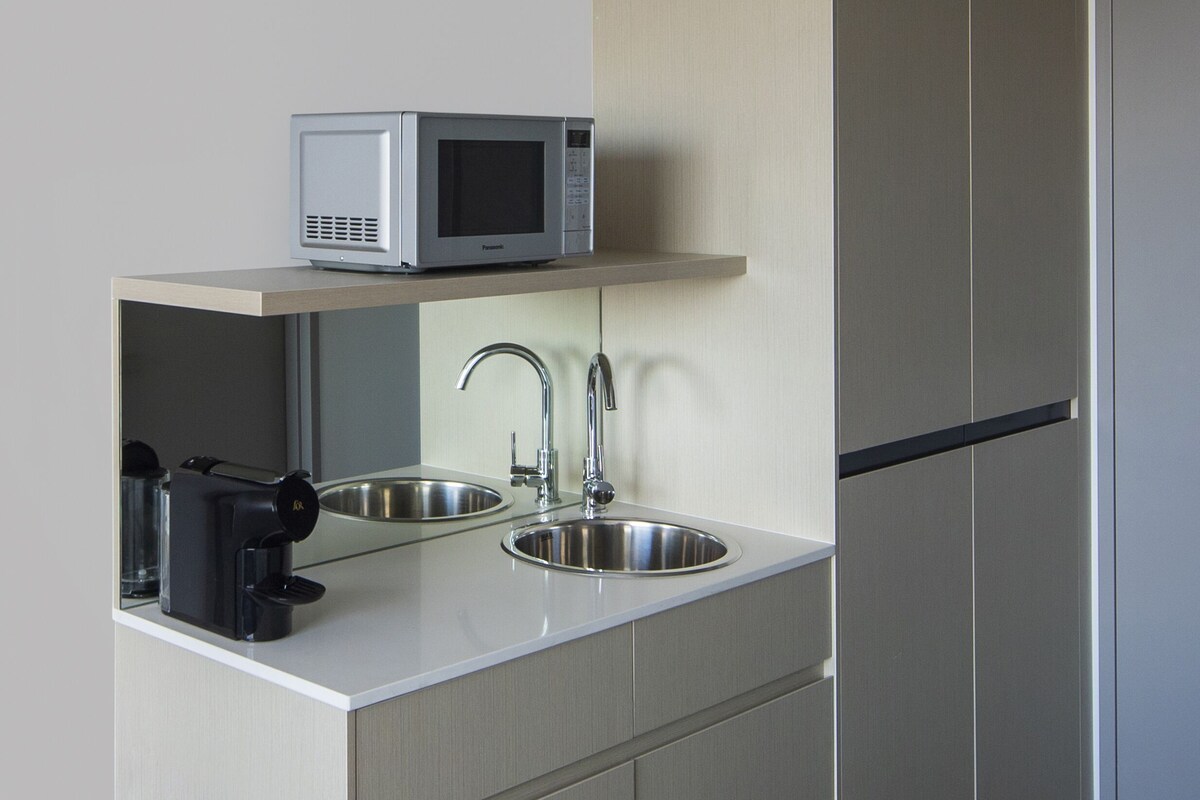 A modern kitchen with a microwave, sink, and coffee maker.