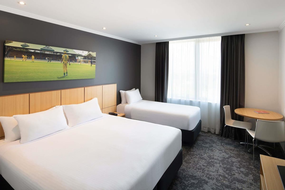 A hotel room with two beds, a small table, and a chair.