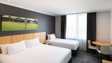 A hotel room with two beds, a small table, and a chair.