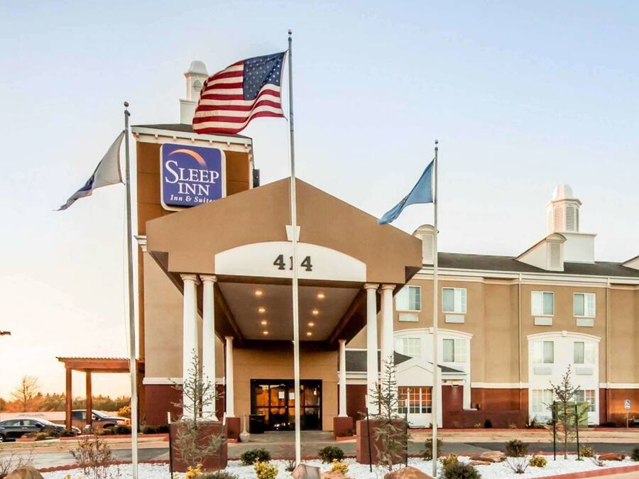 A Sleep Inn hotel with a prominent American flag, a large entrance canopy, and a numbered address sign.