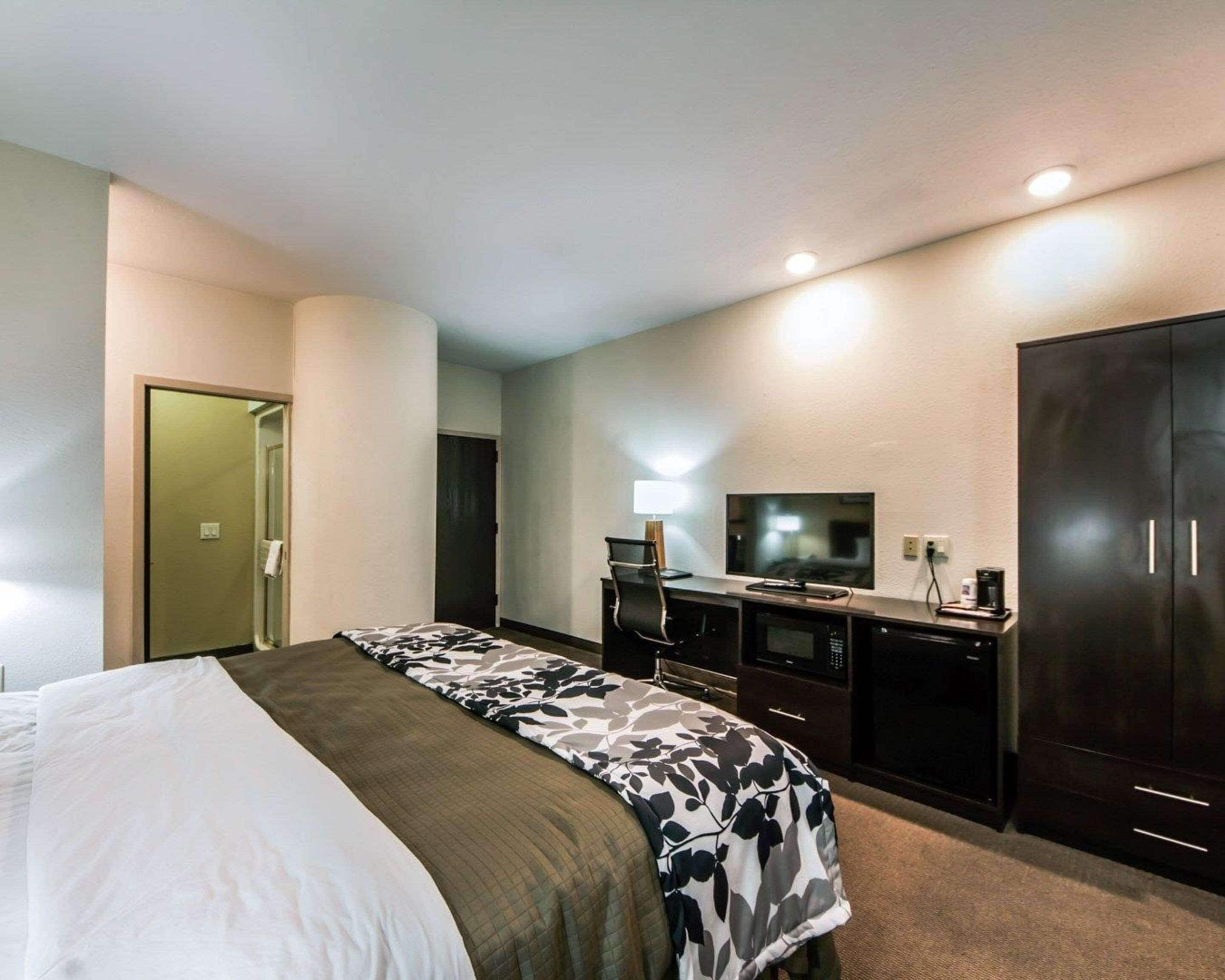 Una habitación de hotel con cama, escritorio con computadora, televisor y armario.