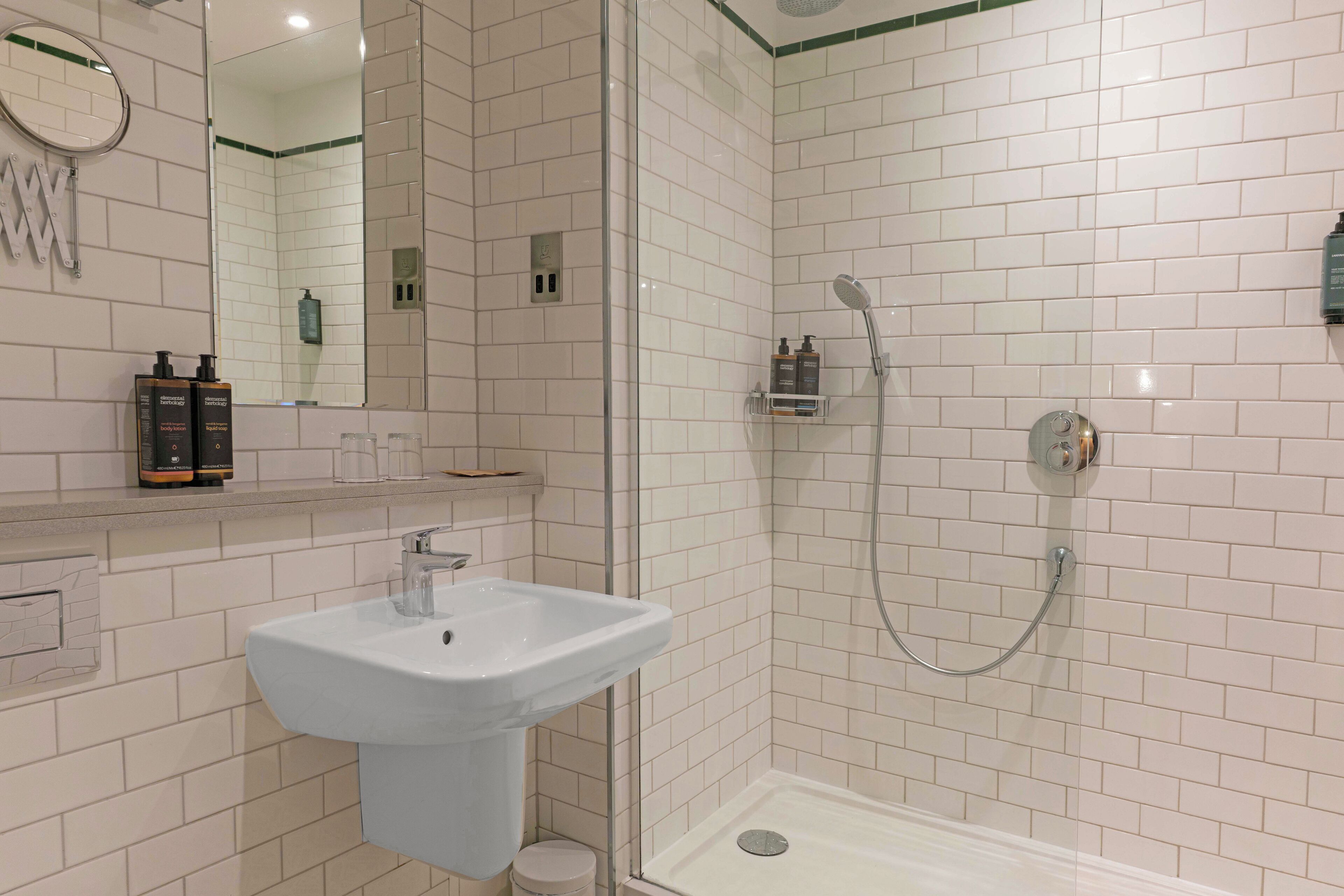 A modern bathroom with a white sink, a glass-enclosed shower, and a mirror above the sink.