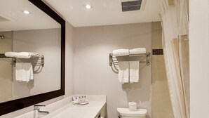 A modern bathroom with a sink, mirror, towel rack, toilet, and shower curtain.