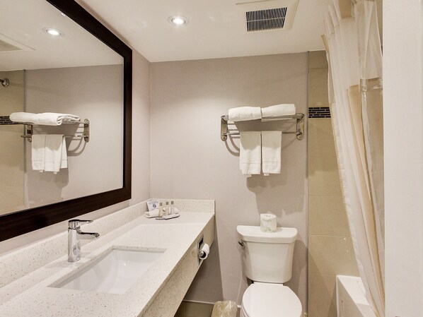 A modern bathroom with a sink, mirror, towel rack, toilet, and shower curtain.