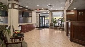 A lobby with a reception desk, chairs, a clock, and a television.