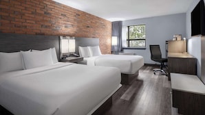 Habitación de hotel con dos camas, un escritorio, una silla y un televisor.
