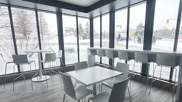 A modern conference room with large windows, a white table, and grey chairs.