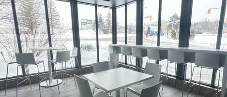 Una sala de conferencias moderna con ventanas amplias, una mesa blanca y sillas grises.