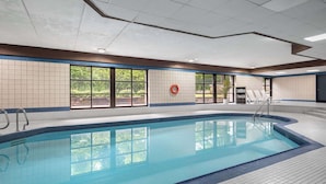 Una piscina con agua cristalina y paredes de azulejos, rodeada de ventanas.