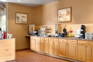 Una cocina con armarios de madera, una estación de café y un ventanal que proporciona luz natural.