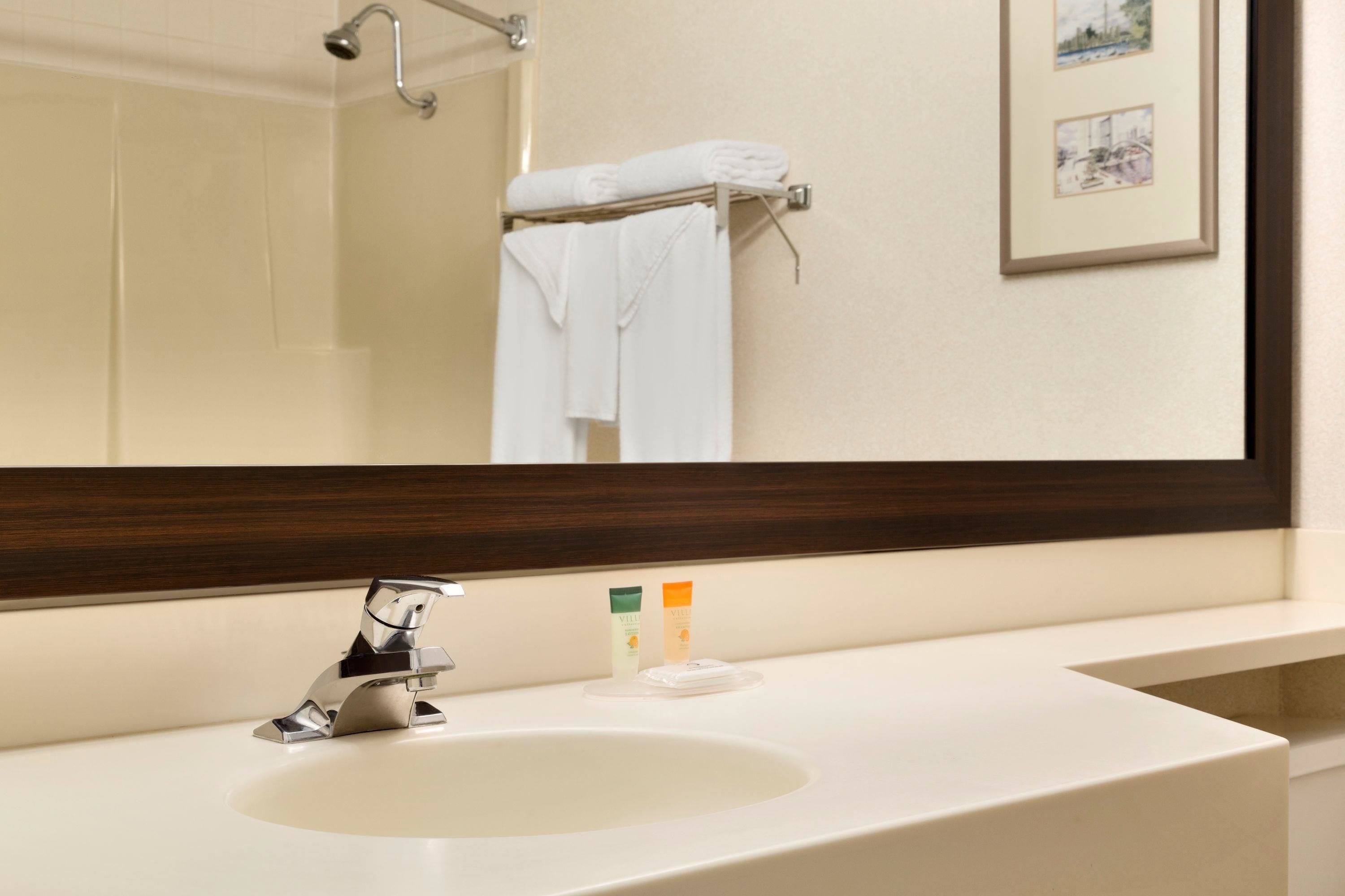 A bathroom with a white sink, a mirror, and a towel rack with a folded towel.