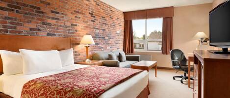 Una habitación de hotel con una cama grande, un escritorio, una silla y un televisor.