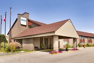 Un hotel Travelodge con fachada de piedra, un acceso cubierto y un estacionamiento con macizos de flores.