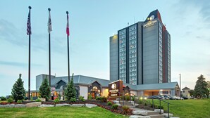 Un hotel con un letrero llamativo de “DOUBLETREE”, un estacionamiento y tres asta de banderas.
