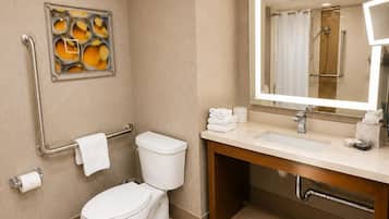 A modern bathroom with a toilet, bidet, sink, and a mirror with a shower visible in the reflection.