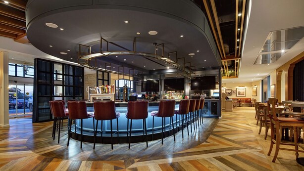 Un área de bar moderna con techo curvo, asientos y barra.