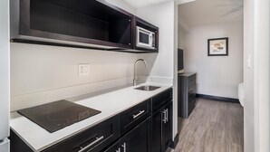 A compact kitchen with a microwave, sink, and black cabinets. - SureStay Hotel by Best Western Virginia Beach Royal Clipper (Virginia Beach)
