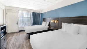 A hotel room with two beds, a desk, and a window with curtains. - SureStay Hotel by Best Western Virginia Beach Royal Clipper (Virginia Beach)