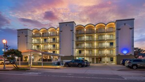 A multi-story hotel with balconies, a covered entrance, and a parking area. - SureStay Hotel by Best Western Virginia Beach Royal Clipper (Virginia Beach)