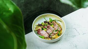 A bowl of food on a marble surface with a green plant in the foreground.