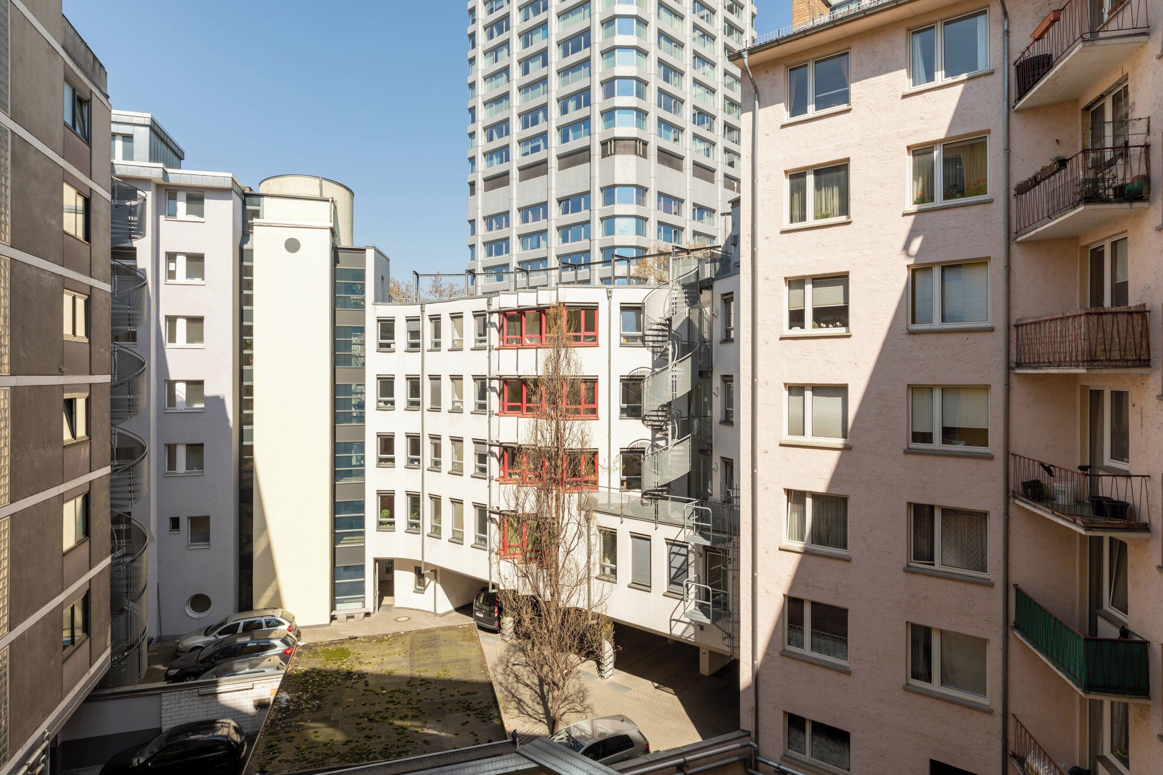 Un edificio residencial de varios pisos con balcones, un patio central y una zona de estacionamiento.