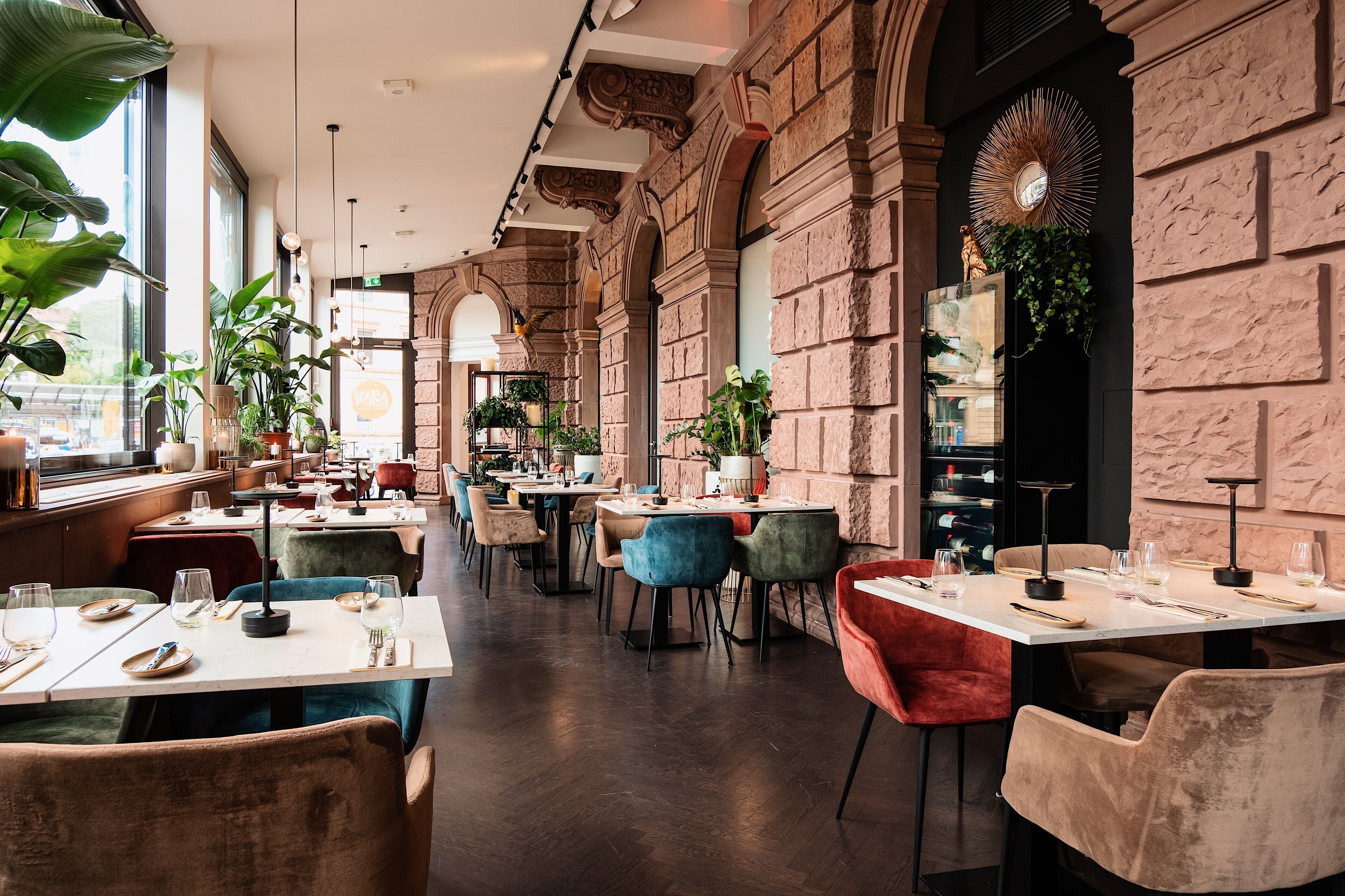 Un restaurant doté de hauts plafonds, de murs en pierre et offrant différents types de sièges, notamment des tables et des chaises.