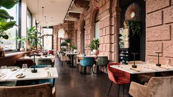 Un restaurant doté de hauts plafonds, de murs en pierre et offrant différents types de sièges, notamment des tables et des chaises.