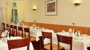 Un comedor con varias mesas dispuestas para el servicio, sillas y un amplio ventanal con cortinas.