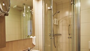 Un baño moderno con ducha de vidrio, lavamanos con espejo e inodoro.