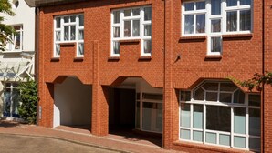 Un edificio de ladrillo rojo con varias ventanas y un acceso cubierto.