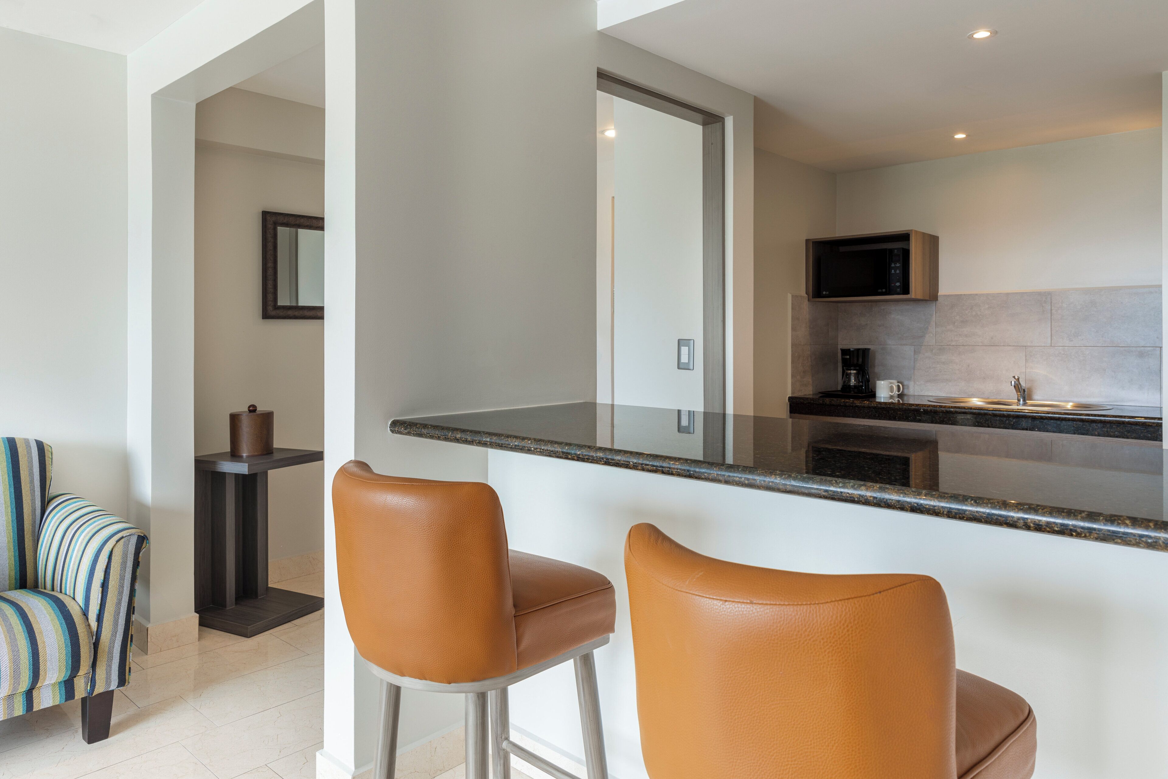 A modern kitchen with a bar area, a microwave, and a coffee maker.