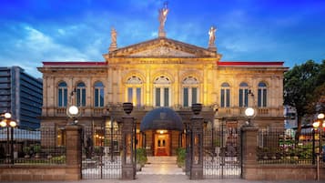 Un edificio imponente con una entrada central, columnas ornamentadas y estatuas en el techo.