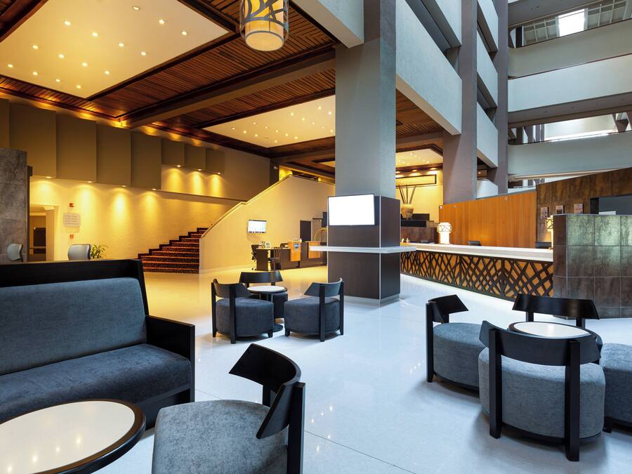 A modern lobby with a reception desk, seating area, and a staircase.