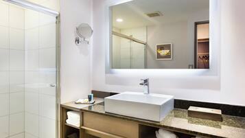A modern bathroom with a glass shower enclosure, a large mirror, and a white sink with a marble countertop.