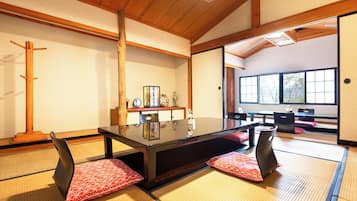A traditional Japanese room with tatami flooring, a low table with cushions, and a sliding door leading to another room.
