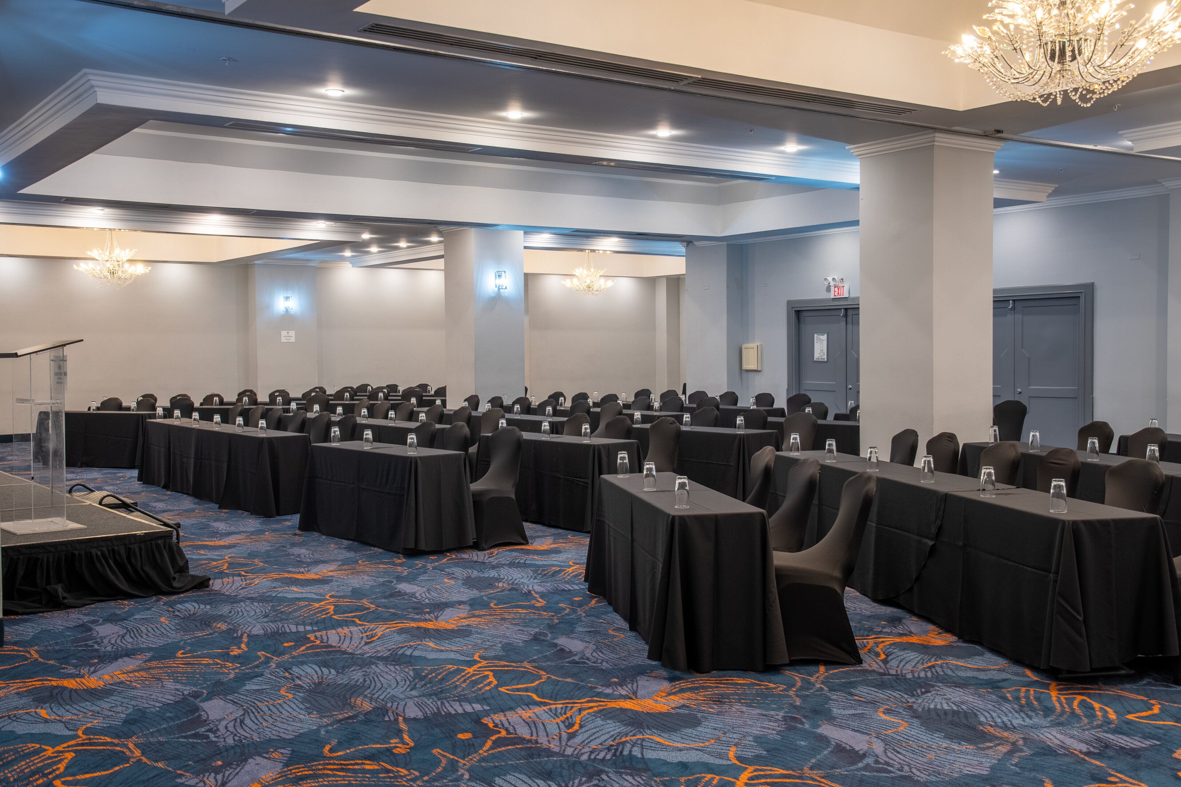 A conference room with rows of tables, chairs, and a podium.