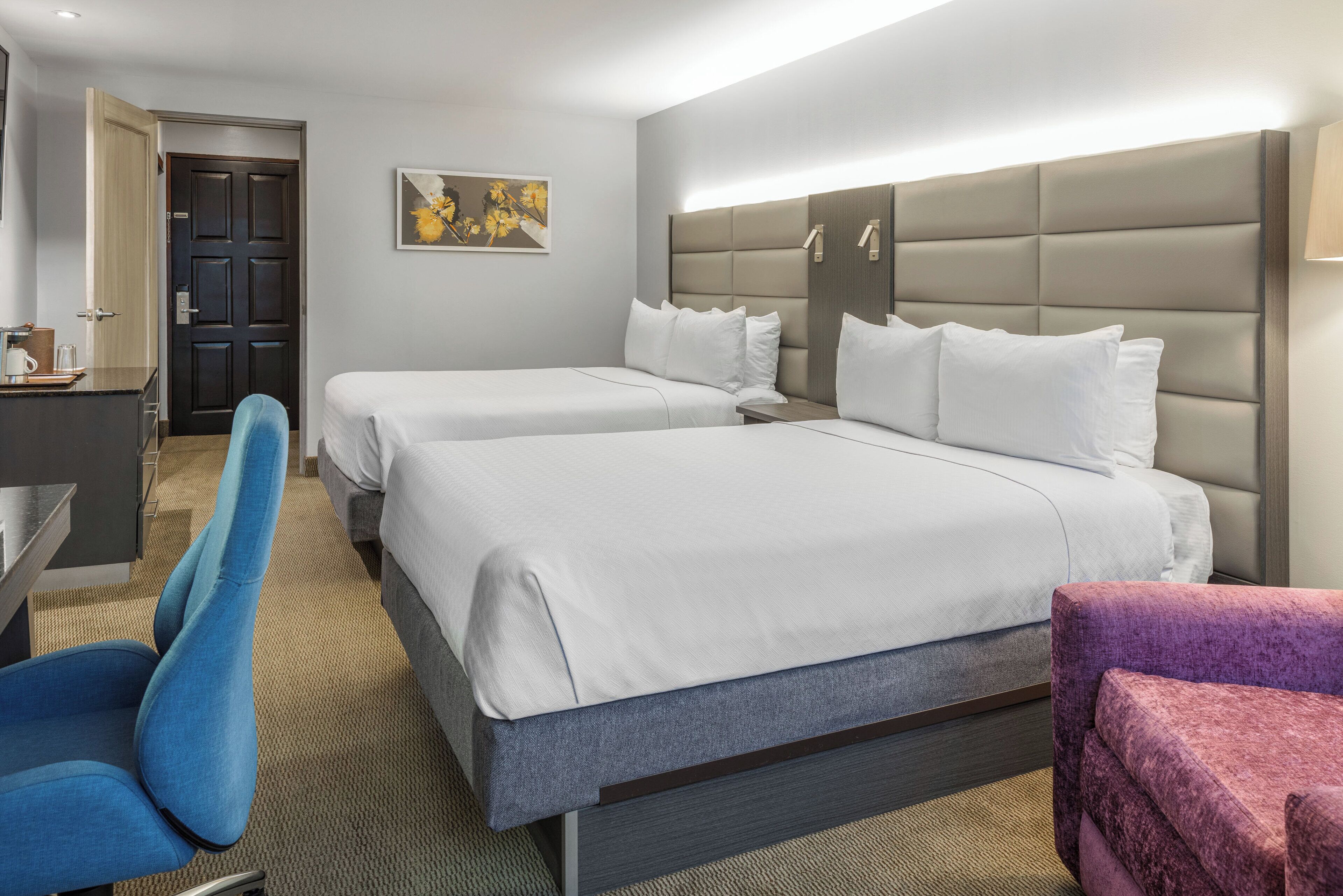 A hotel room with two beds, a desk, and a chair.