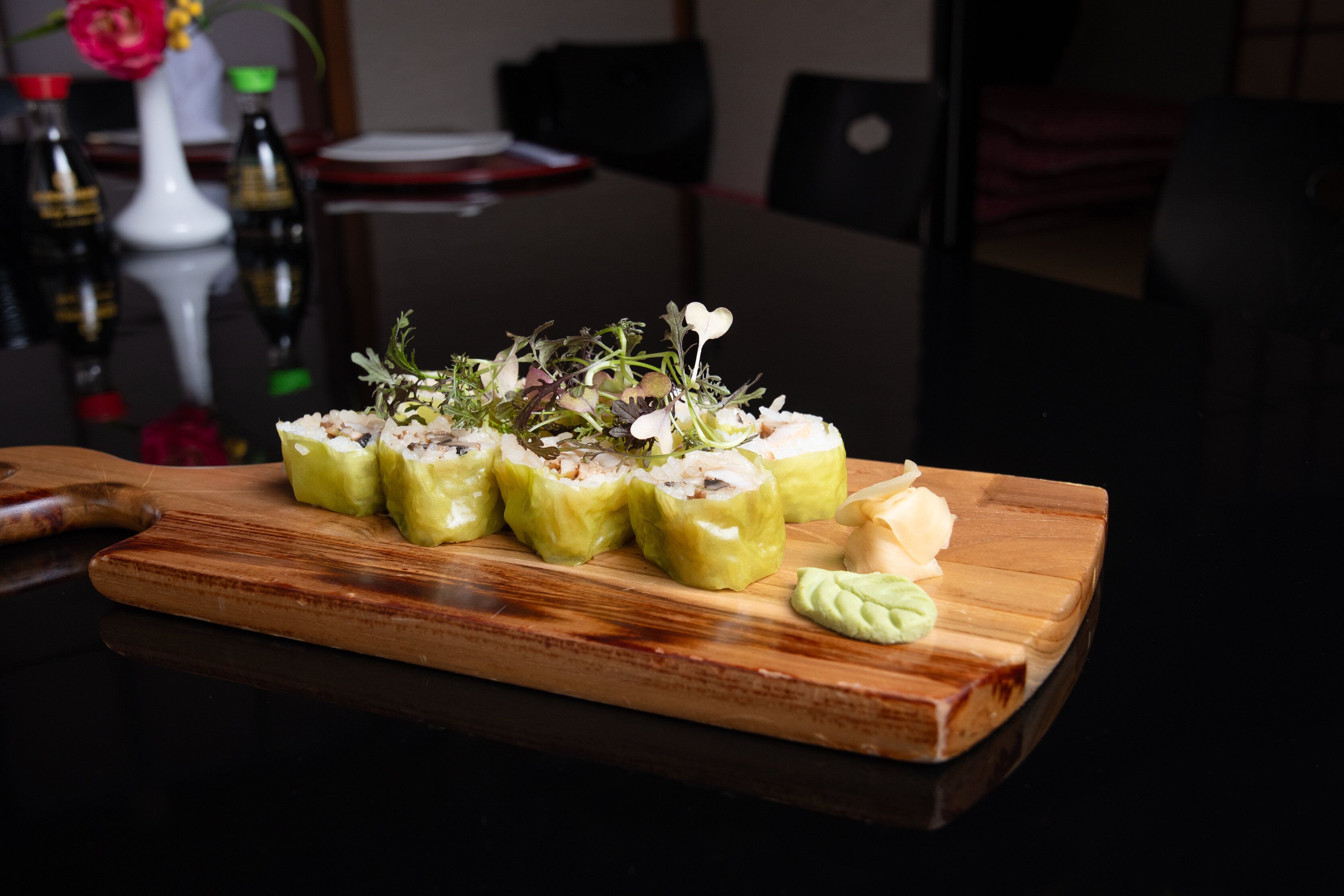 A wooden cutting board with a dish of stuffed vegetables and a small dollop of sauce.
