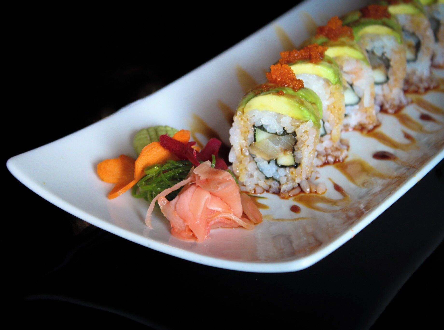 A sushi dish with various toppings and a side salad on a white plate.