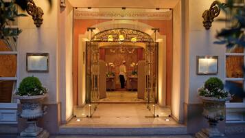 L'ingresso di un hotel con un'imponente arcata, una reception e un cameriere.