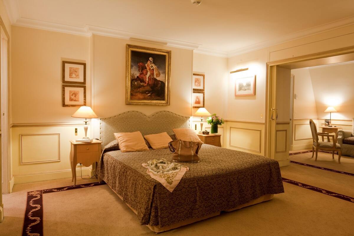 A hotel room with a large bed, two bedside tables, a chair, a desk, and a mirror.