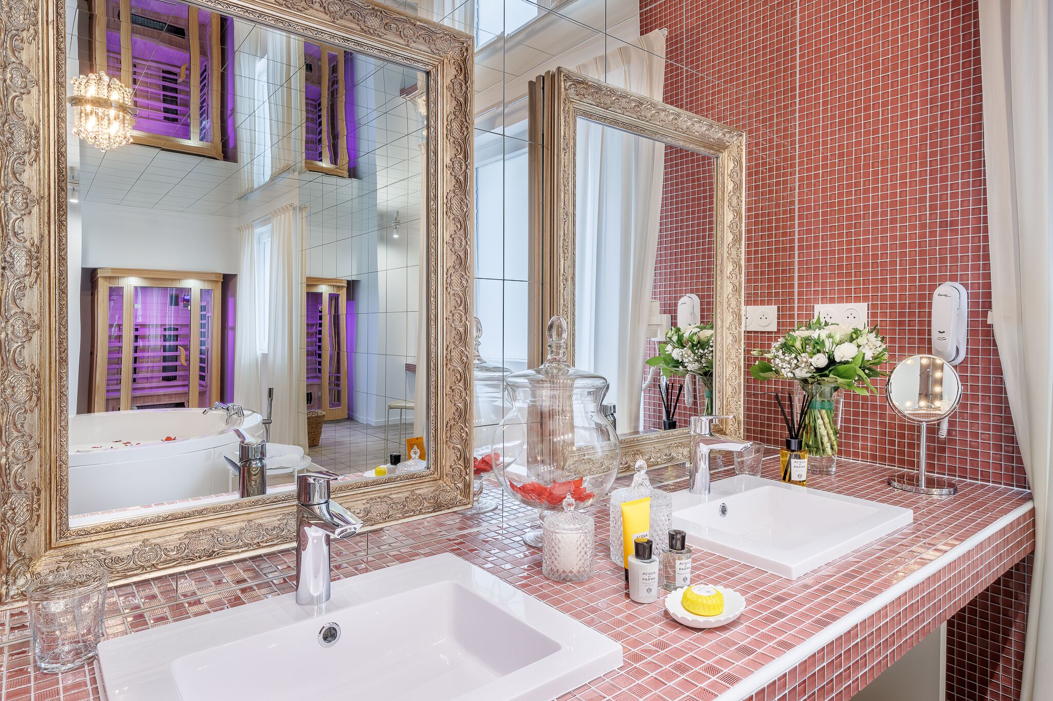 A bathroom with two sinks, a large mirror, and a red-tiled wall.