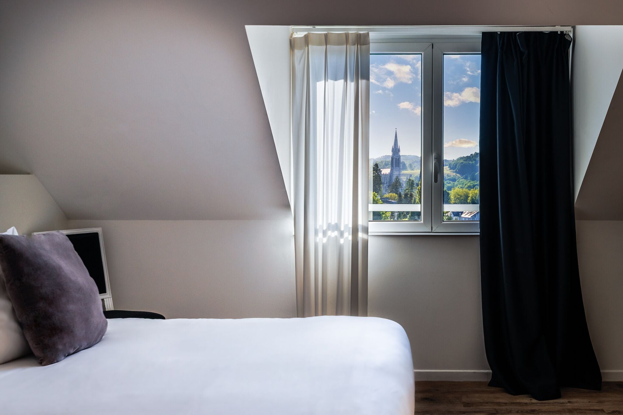 Une chambre à coucher avec un lit, une télévision et une fenêtre avec des rideaux.