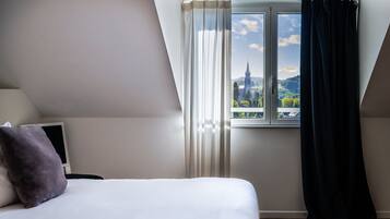 Une chambre à coucher avec un lit, une télévision et une fenêtre avec des rideaux.