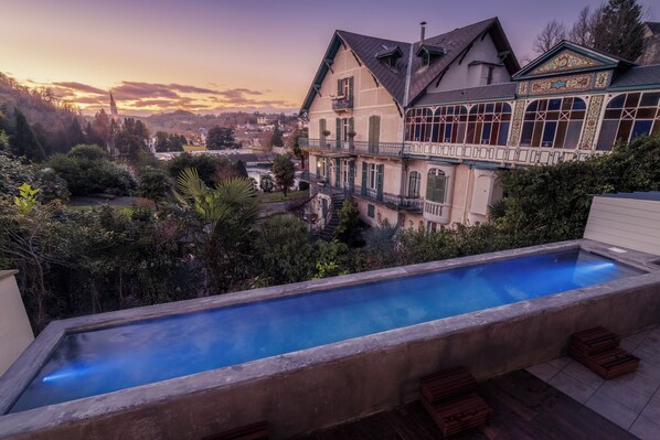 A swimming pool with a view of a large house and a church in the background. - Belfry Spa by Ligne St Barth (Lourdes)